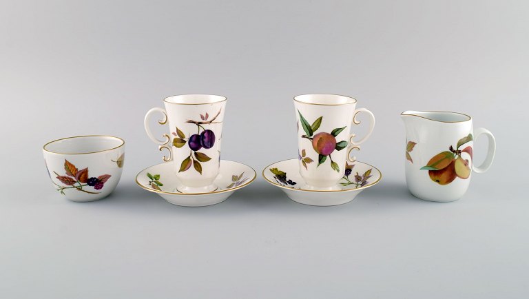 Royal Worcester, England. Two Evesham coffee cups with saucers, sugar bowl and cream jug in porcelain decorated with fruits and gold rim. 1980s.