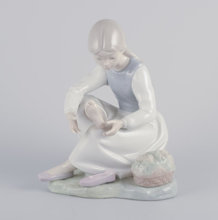 NAO, Spanien.Porcelænsfigur af pige som holder hvil.