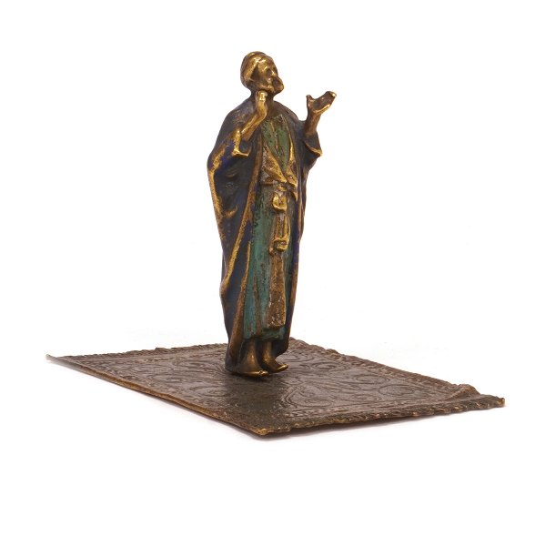 Figur einer orientalischen Person auf einem Teppich. Zinn, dekoriert. H: 9,5cm. Base: 9x11cm